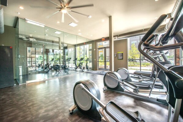 A gym with exercise equipment, a large mirror, and a ceiling fan. - Quiet Getaway | Weekly & Monthly Discounts (Richardson)