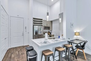 Een moderne keuken met een centraal eiland, roestvrijstalen apparatuur en een eetgedeelte met krukken.