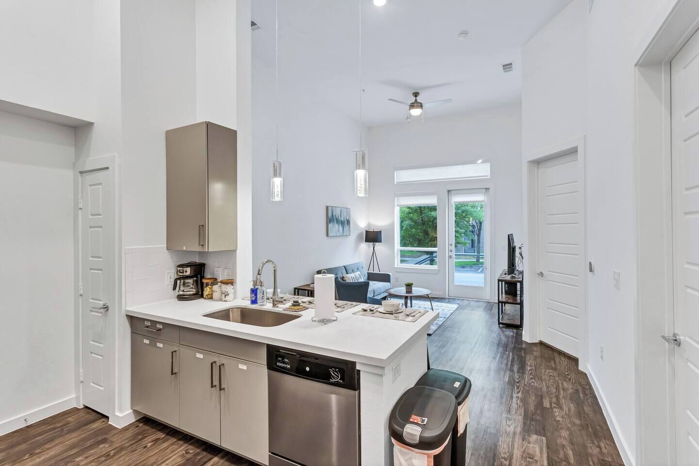 Una cocina moderna con lavavajillas, un comedor con mesa y sillas, y una sala de estar con sofá y televisor.