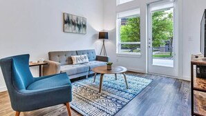 Ein modernes Wohnzimmer mit einer Couch, einem blauen Sessel, einem Couchtisch und einem gemusterten Teppich.