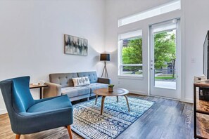 Een moderne woonkamer met een bank, een blauwe fauteuil, een salontafel en een kamerbreed tapijt.