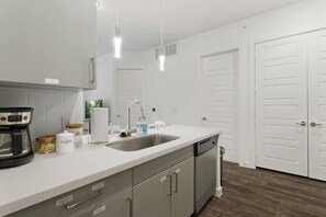 A modern kitchen with a dishwasher, coffee maker, and storage cabinets. - Relax & Save | Weekly & Monthly Discounts (Richardson)