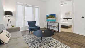 Una sala de estar moderna con un sofá, un sillón azul, una mesa de centro y un televisor sobre un mueble.
