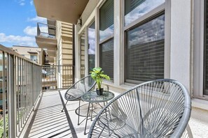Ein Balkon mit zwei Metallstühlen, einem kleinen Tisch und einem Blumentopf.