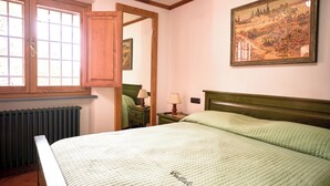 A bedroom with a bed, a window, a radiator, a nightstand, a lamp, and a painting on the wall. - Collalceppo, Villa Le Sorbe, featuring wood-paneled interiors and spacious outdoor areas (Toscana)