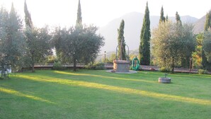A grassy outdoor area with a stone fountain, trees, and a stone wall. - Collalceppo, Villa Le Sorbe, featuring wood-paneled interiors and spacious outdoor areas (Toscana)