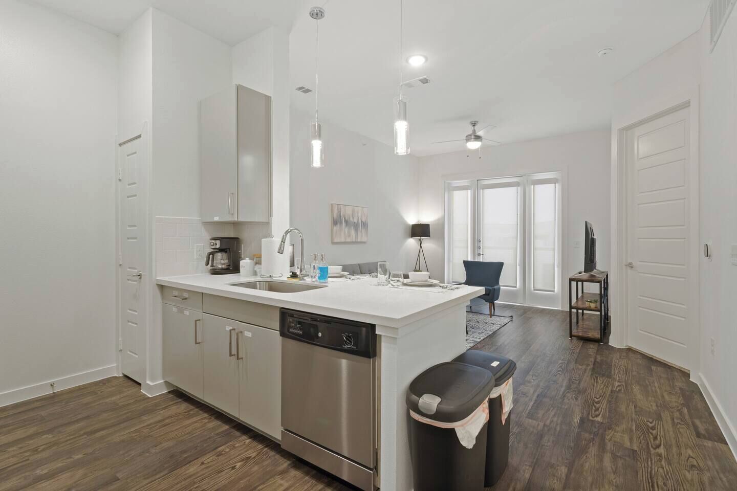 A modern kitchen with a dishwasher, a sink, and a dining area with a chair and a table.