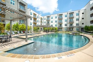 Uma piscina com toldo, cadeiras de descanso e aviso de proibição de mergulho.
