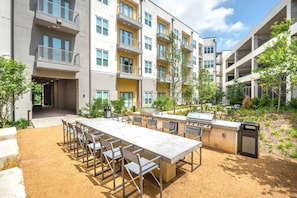 A multi-story building with outdoor seating, a barbecue area, and a trash bin. - Near Trails & Eats | Weekly & Monthly Specials (Richardson)