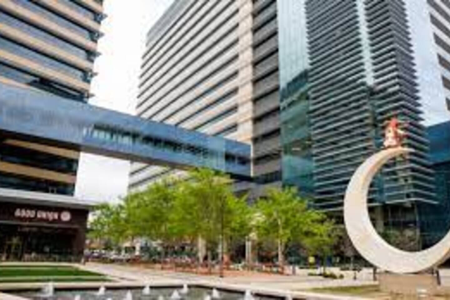 Una zona urbana moderna con edificios altos, una estructura circular y un edificio con un letrero.