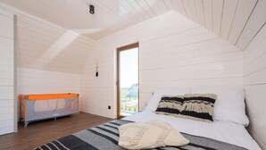 A bedroom with a bed, a window, a door, and a baby playpen. - Pleasant 2-bedroom house with AC in charming Mielenko (Mielenko)