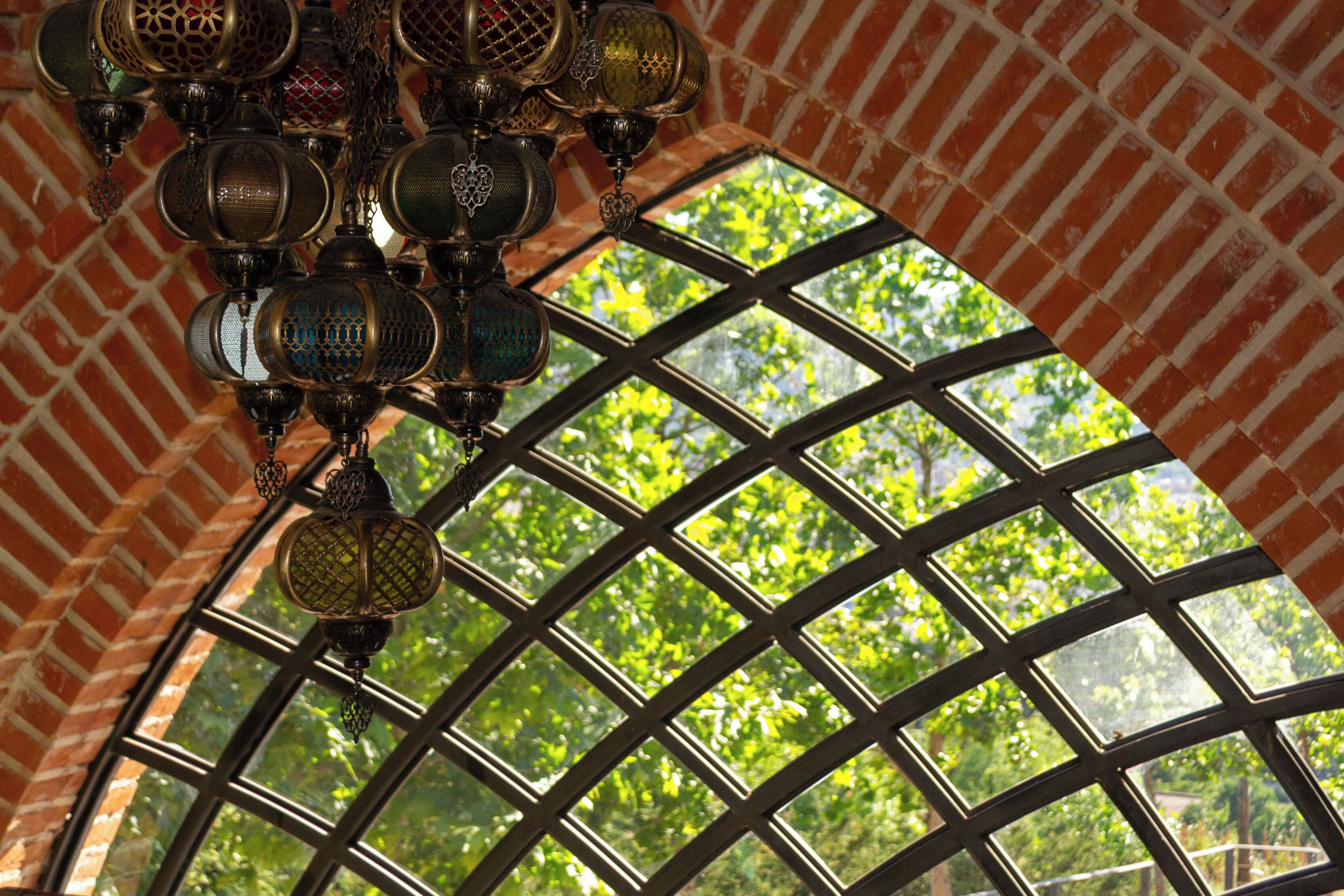 A room with a large window, a brick wall, and hanging decorative lamps.