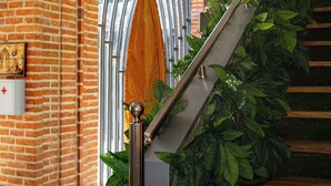A staircase with a metal railing, brick walls, and green foliage. - Citadel 360 Suites & Spa (Skopje)