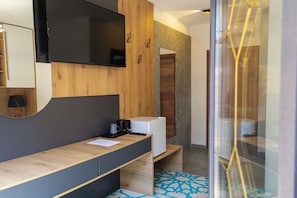 A modern bathroom with a wooden vanity, a mirror, a flat-screen TV, and a white refrigerator. - Citadel 360 Suites & Spa (Skopje)