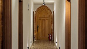 A hallway with a wooden door, a fire extinguisher, and a ceiling light fixture. - Citadel 360 Suites & Spa (Skopje)