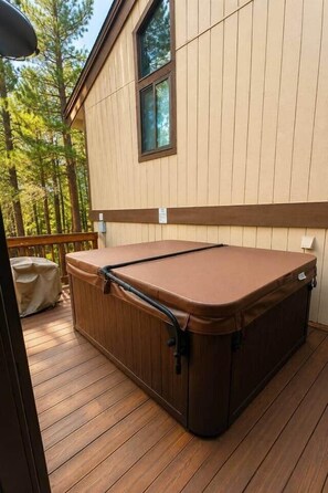 A hot tub on a wooden deck with a view of a forested area. - Charming Stateline Condo (Round Hill Village)