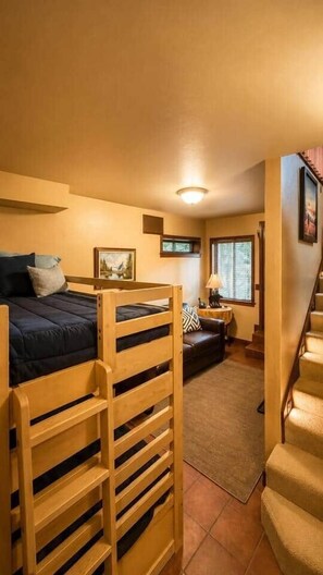 A room with bunk beds, a sofa, a small table, and a staircase. - Charming Stateline Condo (Round Hill Village)