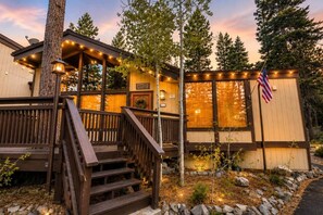 A cabin with a wooden deck, a front porch, and an American flag. - Charming Stateline Condo (Round Hill Village)