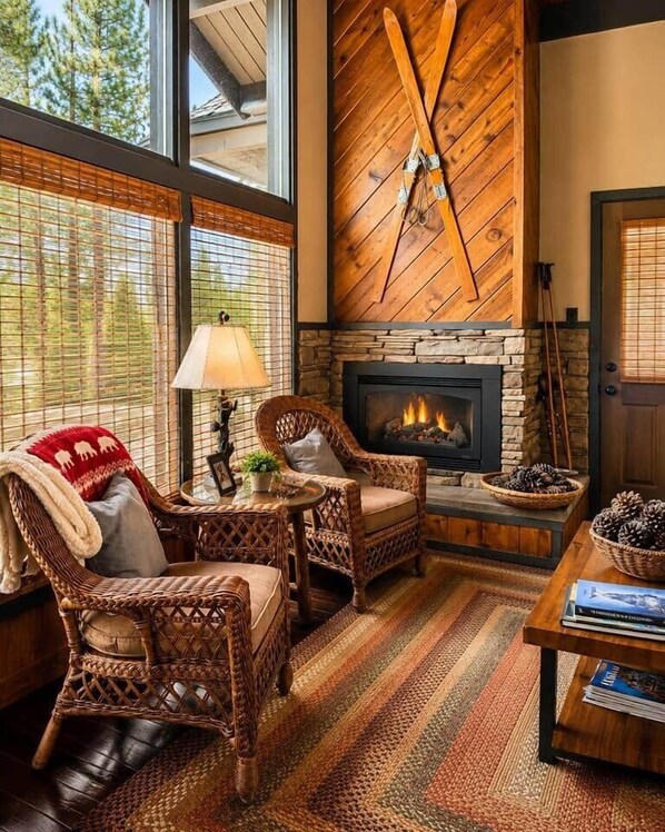 A cozy living room with wicker furniture, a fireplace, and a large window with blinds. - Charming Stateline Condo (Round Hill Village)