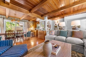 A spacious living room with a wooden ceiling, a sofa set, a dining area with chairs, and a kitchen in the background. - Zephyr Cove Gem - 2-min walk to HOA Beach! (Zephyr Cove)