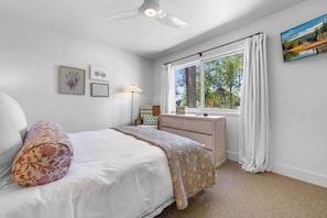A bedroom with a bed, a desk, a window with curtains, and wall art. - Zephyr Cove Gem - 2-min walk to HOA Beach! (Zephyr Cove)