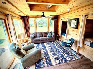 A cozy cabin interior with a sofa, armchair, and a patterned rug. - Boutique Northwoods Lake House - Sandy Beach - ATV Access - Sleeps 10 (Fence)