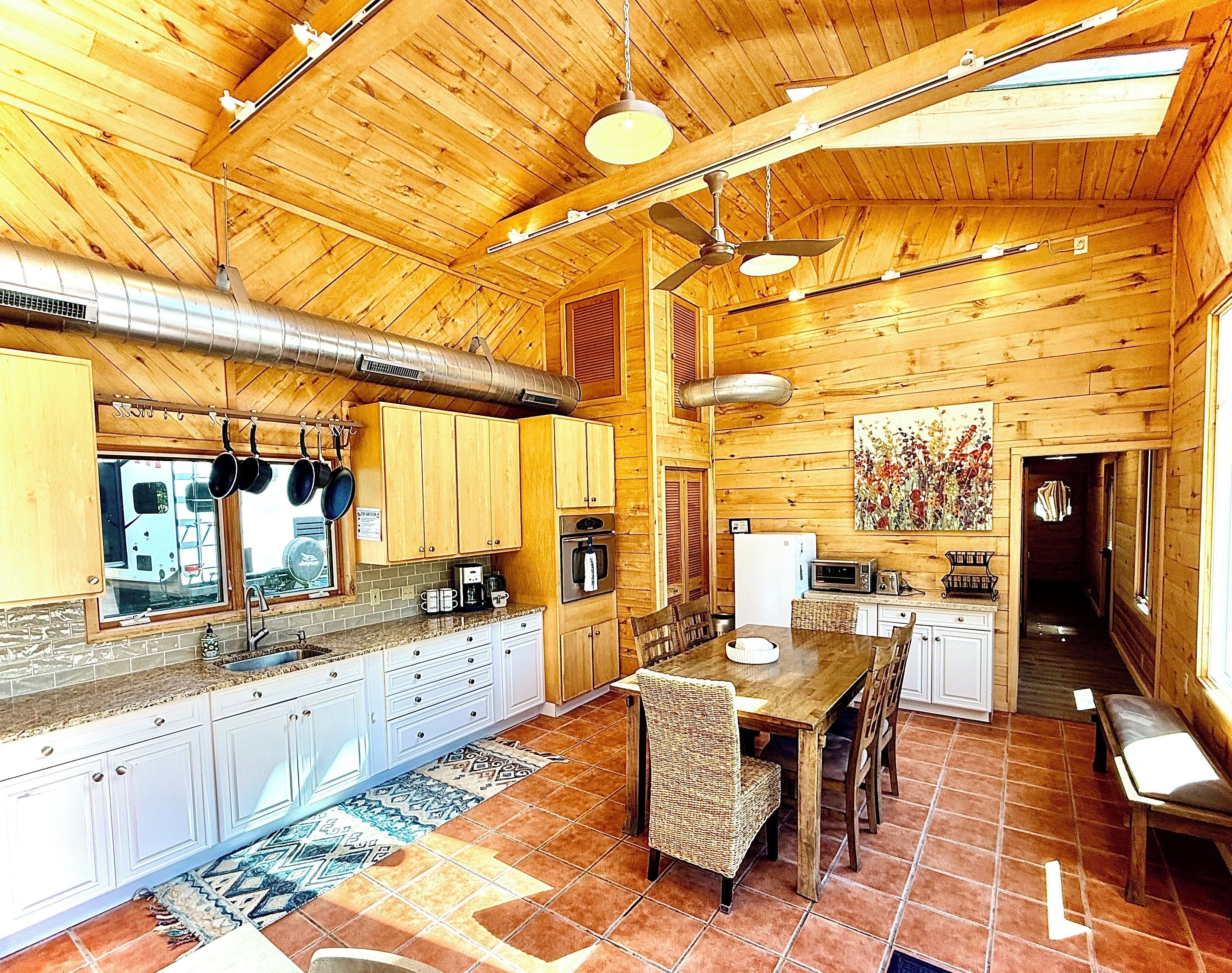 A wooden cabin interior with a kitchen, dining area, and a hallway.
