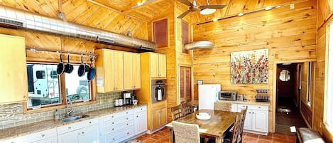 Interior de una cabaña de madera con cocina, comedor y un pasillo.