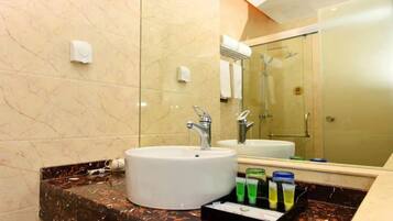 A bathroom with a white sink, a mirror, and a glass shower enclosure.