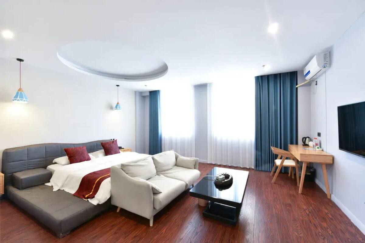 Una camera d'hotel moderna con un divano letto, un piccolo tavolo da pranzo, un tavolino e una TV.