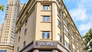 Un hotel de varios pisos con entrada en esquina, ventanas amplias y un letrero que indica un restaurante en la planta baja.