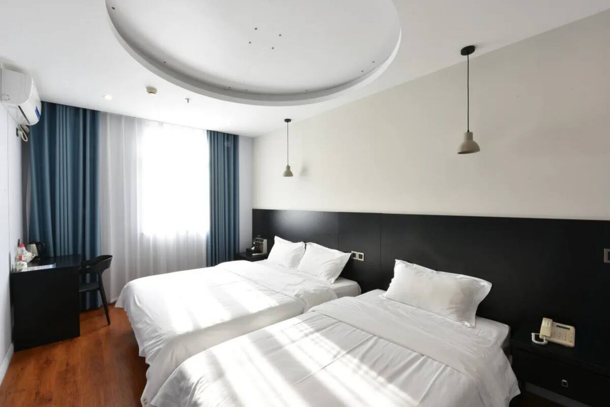 Camera d'albergo con due letti, una scrivania, una sedia e un telefono sul comodino.