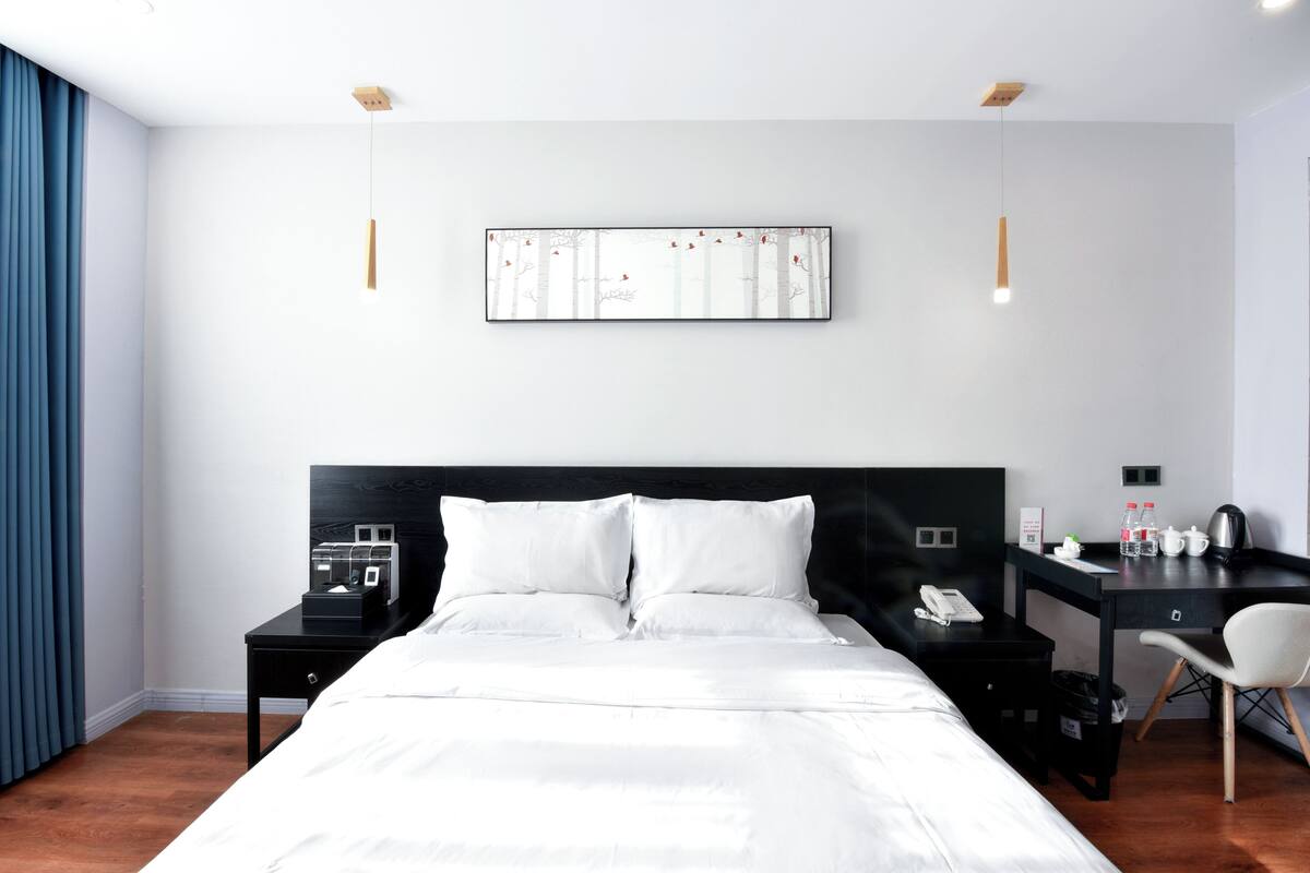 Una moderna camera d'albergo con un letto grande, una scrivania, una sedia e un quadro appeso al muro.