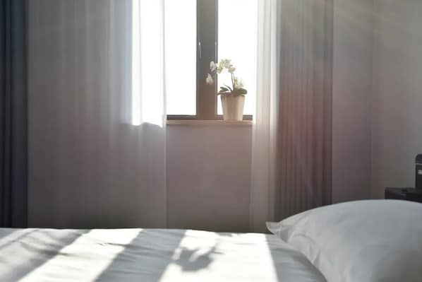 A bedroom with a bed, a window with curtains, and a potted plant on the windowsill. - Xiamen Yisan Mamba Hotel (Xiamen)