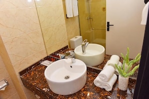A bathroom with two sinks, a glass shower enclosure, and a potted plant. - Xiamen Yisan Mamba Hotel (Xiamen)