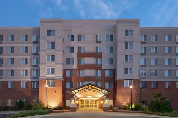 A multi-story hotel with a central entrance, large windows, and a brick facade.