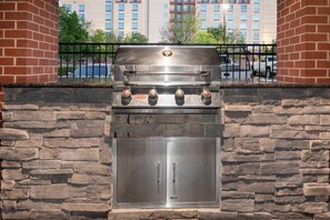 Una pared de piedra con una parrilla empotrada y un horno de acero inoxidable.