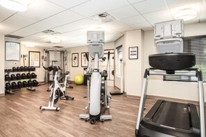 Un gimnasio con máquinas de cardio, mancuernas y una cinta de correr.