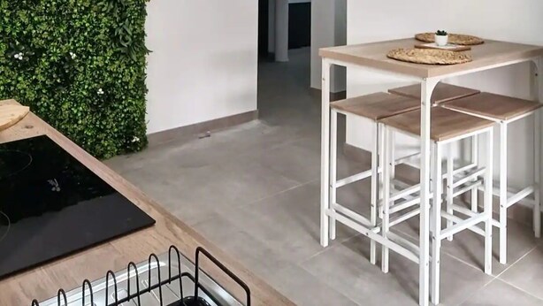 Ett modernt kök med en neonreklamskylt, en matplats med barstolar och en väggmonterad neonreklamskylt.