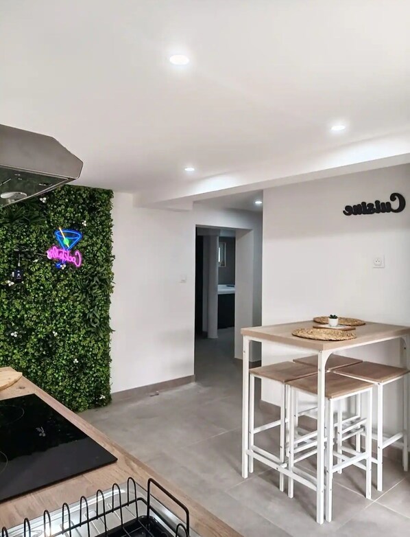 A modern kitchen with a neon sign, a dining area with stools, and a wall-mounted neon sign.