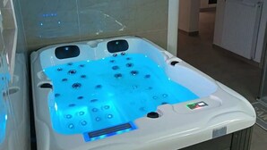 A modern bathroom with a large, white, freestanding bathtub featuring multiple jets and a control panel.