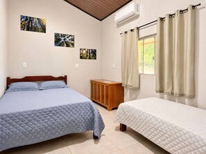 Un dormitorio con dos camas, un armario de madera y tres cuadros en la pared.