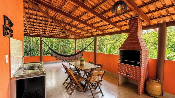 Un patio exterior con una parrilla, mesa de comedor, sillas, una hamaca y un horno de ladrillo.