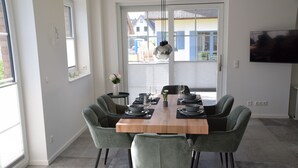 A dining area with a wooden table, six chairs, and a hanging light fixture. - Sturmvogel Vacation Home (Dranske)