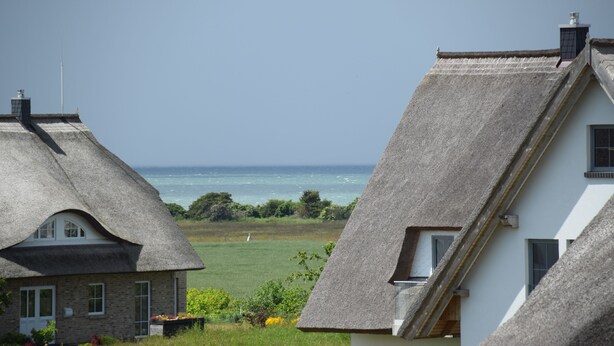 A coastal house with a thatched roof, a visible chimney, and a view of the sea. - Sturmvogel Vacation Home (Dranske)