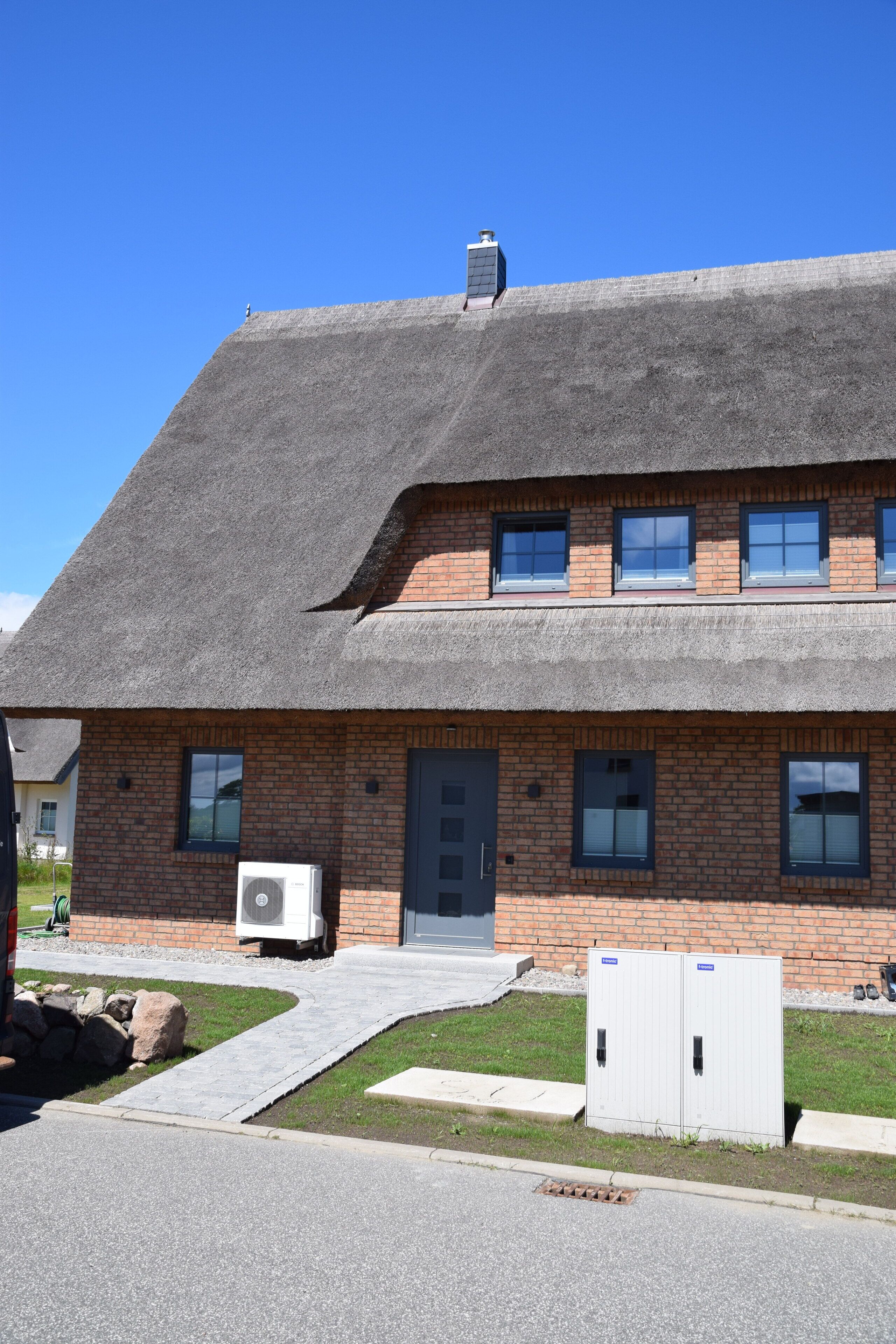 Un bâtiment à deux étages, doté d’une façade en briques, d’un toit de chaume et d’une petite cheminée.