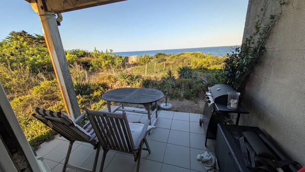 An outdoor patio with a table and chairs, a barbecue grill, and a view of the sea. - CHEZ NICO: A breathtaking view of the Atlantic Ocean. The dune is your garden. (Soulac-sur-Mer)