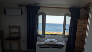 A bedroom with a bed, a chair, a dresser, and a window with a view of the sea. - CHEZ NICO: A breathtaking view of the Atlantic Ocean. The dune is your garden. (Soulac-sur-Mer)