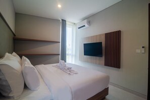 Camera d'albergo con un letto, cuscini, una TV a schermo piatto montata a parete e un condizionatore d'aria.