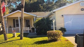 A single-story house with a front porch, a garage, and a well-maintained lawn. - Peaceful 3-bedroom house with AC in Flagler Beach (Flagler Beach)